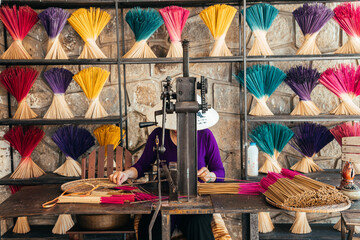 a woman is making incense sticks from sandalwood 