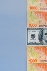 view of half bills of 1000 Argentine pesos with one of 100 dollars with the dollar bill in the middle and half space for text, vertical image