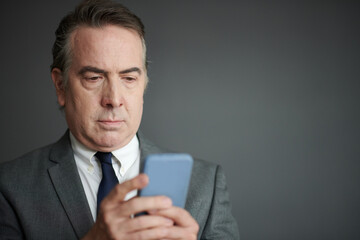 Portrait of serious businessman reading news and notifications on smartphone