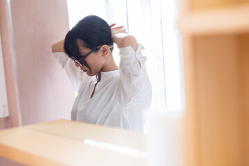 髪を束ねる女性　A woman tying her hair in the bathroom