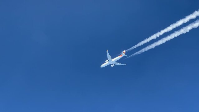 External view of a massive white Airbus 330 and its wake shot from the cockpit of another jet fliying bellow