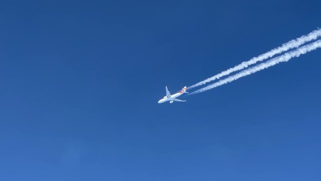 A massive  white Airbus 330 jet and its wake  shot from the cabin of another jet flying bellow.