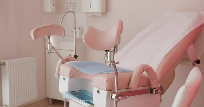 Gynecological chair in pink tones at private cabinet of hospital. Professional medic equipment for woman's examination or inspection. Health care concept