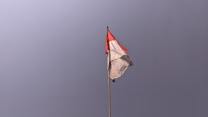 The red and white Indonesian flag flutters against a blue sky background