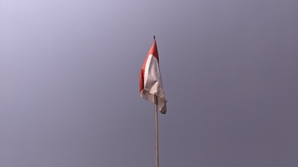 Fototapeta premium The red and white Indonesian flag flutters against a blue sky background