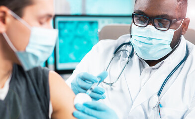 African-American doctor makes a coronavirus vaccine using a syringe and hypodermic needle....