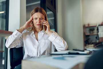 Worried woman manager makes business call and listens client claim while sitting in modern office