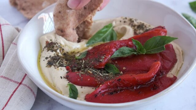 Hummus bowl with spices, grilled peppers and basil. Vegan food, Israeli cuisine, plant-based diet concept.