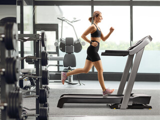 Fototapeta na wymiar Profile shot of a fit strong woman running on a treadmill