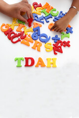 Hands of mom and daughter playing with colored letters that form ADHD Attention Deficit...