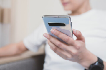 Using a smartphone for everyday purposes at home. Close-up on the phone in woman hand. Selective soft focus.