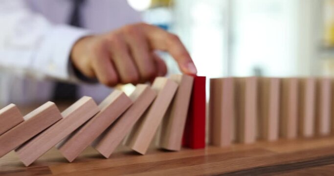 Falling of ordinary figurines stopped by red wooden block placed on wooden table. Compensation and personal accident insurance service. Domino effect concept