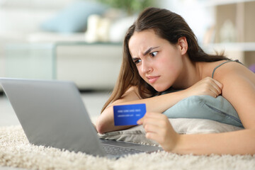 Confused woman buying online with laptop at home