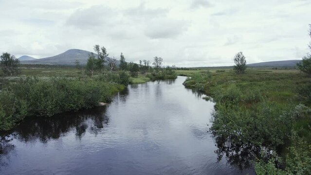 Peaceful river flows through remote Norway plateau on breezy day