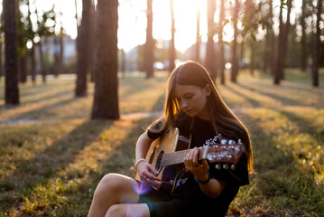 girl with guitar . Smiling young asian woman learning to play guitar in park, musician concept,...
