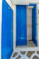 Entrance of a traditional house of typical Cycladic architecture with blue doors and white walls, in Mykonos island, Cyclades islands, Greece, Europe. 