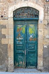 Old weathered wooden door with amazing stone arched lintel at an abandoned old mansion in Old Town of Rethymno, in Crete island, Greece, Europe. 