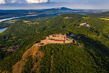 Visegrad, Hungary - Aerial drone view of the beautiful high castle of Visegrad with summer foliage and trees. Dunakanyar and blue sky with clouds at background on a sunny day