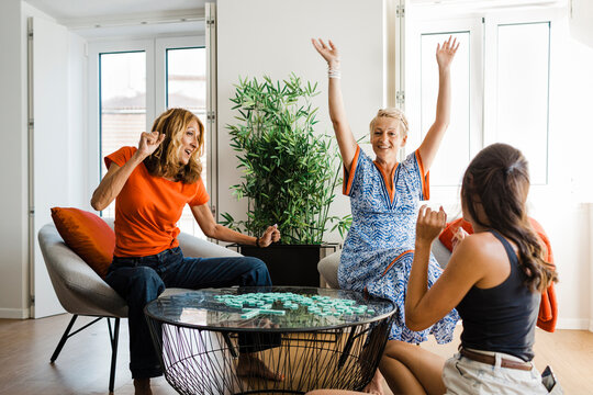 Cheerful friends playing word games and enjoying in apartment