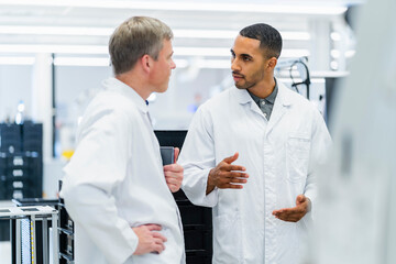 Team of competent electrical technicians in lab coats having meeting in electronics factory