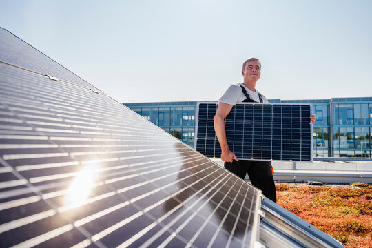 Craftsman carrying solar panel on the roof of a company building