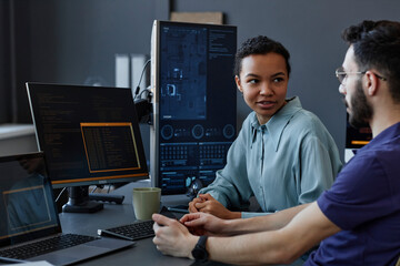 Smiling young computer programmers discussion together at desk in office