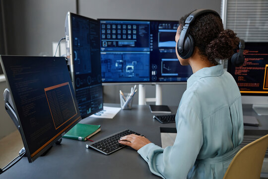 Computer programmer coding and working on desktop PC at desk