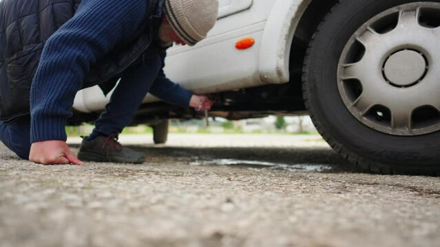 A man uses a handle to drain grey waste water from a caravan. Service maintenance.