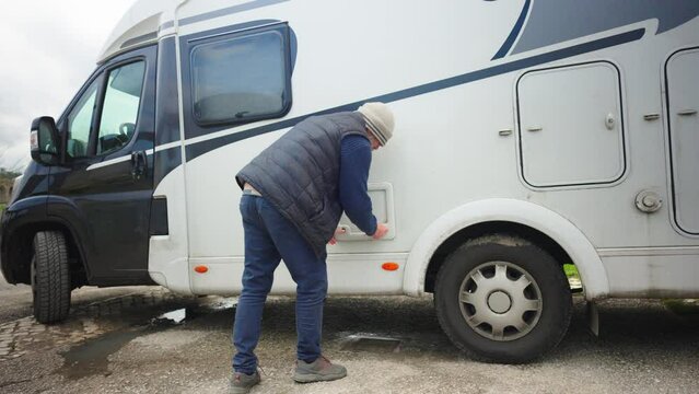A man pulls a toilet waste container out of a caravan