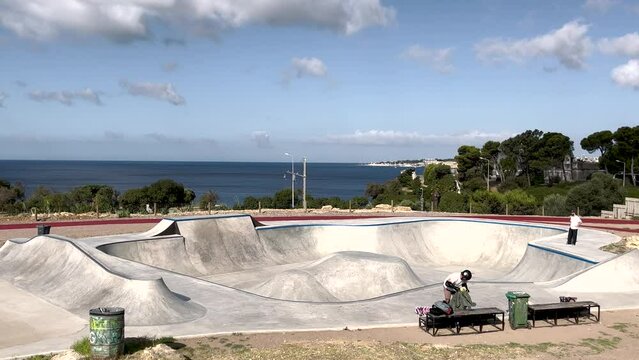 A skater smoothly navigates the empty Estoril skatepark pool, enhancing skills and fluidity, incorporating surfing elements into their technique.