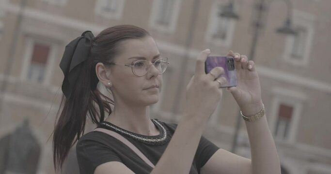A beautiful girl with glasses takes a photo with her phone while on vacation in Italy. Shot in 4K recorded in log.