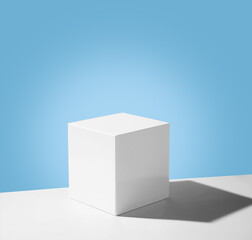 White cube empty for product demonstration or mock-up on a blue background with shadow. Generated AI. Trendy neutral aesthetic  stand for beauty and cosmetics scene.