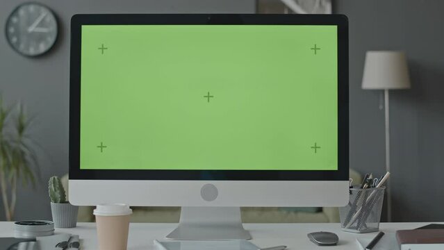No people shot of computer desktop with green template screen on work desk in contemporary office