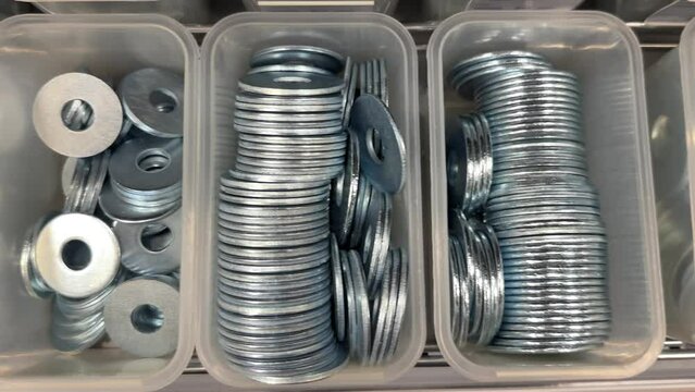 Boxes with many Stainless Steel Flat Washers, Metal Plain Gasket Rings in various sizes in Hardware Store, close-up top view.
