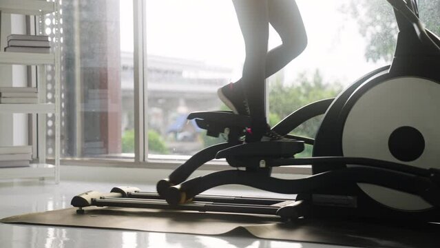  woman in sportswear exercising on an exercise bike at home