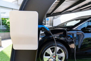 Electric car is charged from a charging station that takes energy from solar panels. Close up
