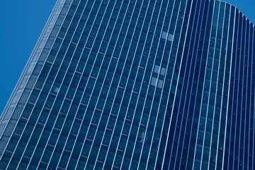 Modern-looking skyscraper with blue-colored glass windows. Modern, stylish, financial or corporate, high-rise headquarters building. Abstract dark blue office building with a white grid pattern. 