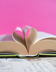 Heart from a book page on pink background, book of love