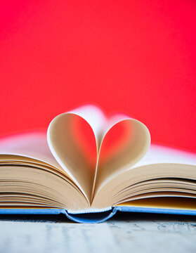 Heart from a book page on red background, book of love