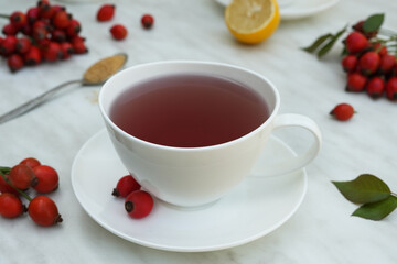 Tea herbal drink from rose hips in glass cup on light background. Side view.