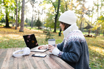 Freelancer working on laptop in autumn park