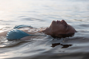 middle aged woman enjoying swimming in the sea lying on her back at sunset. Slow life. Enjoying the...