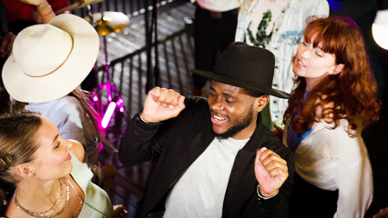 Young african american man dancing on a rooftop party enjoying time with friends. Fun time with friends enjoying rooftop party music, celebrating weekend reunion gathering.