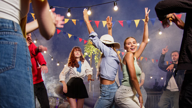 Young Caucasian Women Dancing And Laughing On A Rooftop Party. Fun Time With Friends Enjoying Rooftop Party Music, Celebrating Weekend Reunion Gathering.