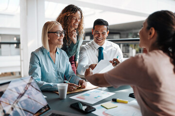 Diverse smiling businesspeople going over paperwork during an office meeting