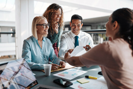 Diverse smiling businesspeople going over paperwork during an office meeting