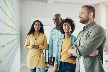 Diverse businesspeople talking while brainstorming with adhesive notes on an office wall