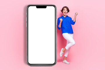 Full body size photo of young excited overjoyed woman fists up smartphone display application for business plans isolated on pink color background