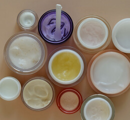 Many jars of beauty cream or mask for face care on pastel background, top view. Concept of skincare cosmetic, cosmetic spa medical skin care. Natural cosmetics concept. Sunlight and shadow.