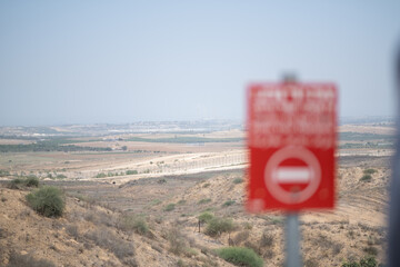 View of the Gaza Strip from Israel. In the foreground, a red warning sign orders people not to...